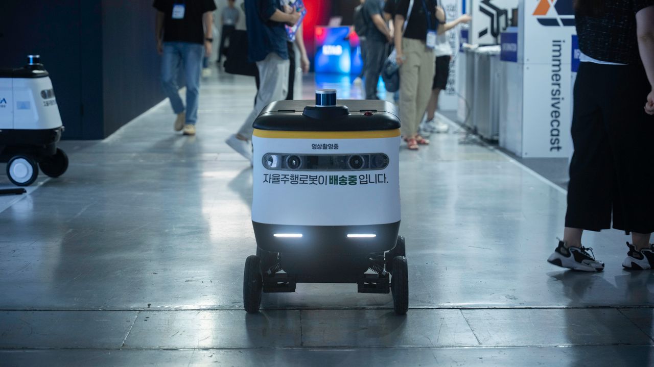 services-03 Autonomous delivery robot navigating indoors during a technology event.